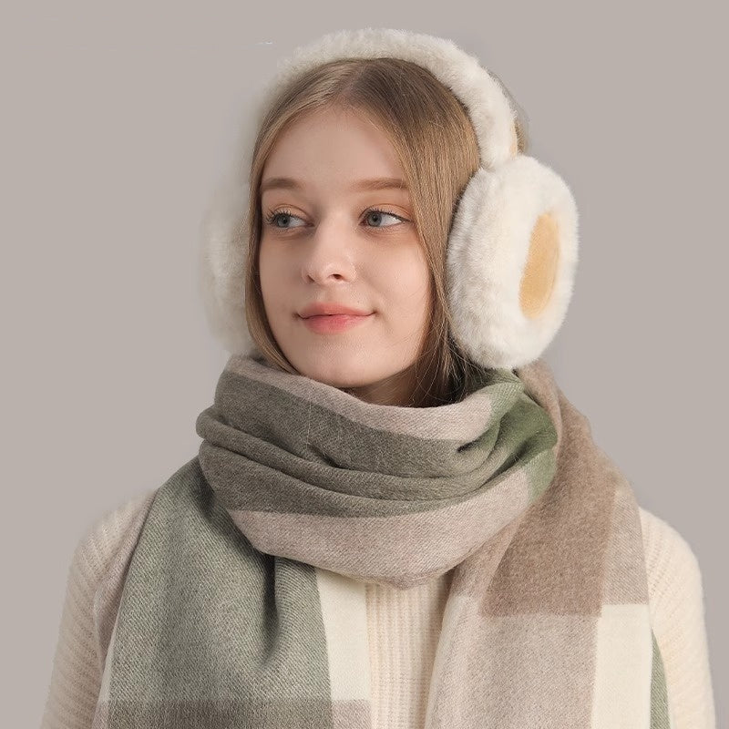 Woman wearing cute warm plush earmuffs, scarf, and gloves in neutral tones.